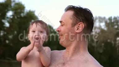 小湿澡的孩子<strong>拍拍</strong>手，笑着坐在爸爸的怀抱里